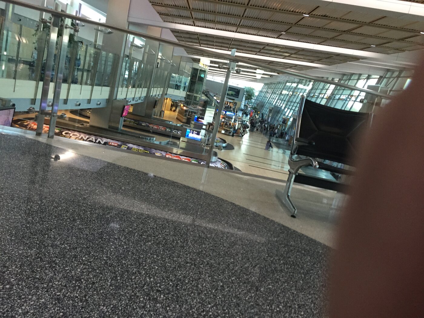 An airport baggage claim photographed with a thumb partially over the lens