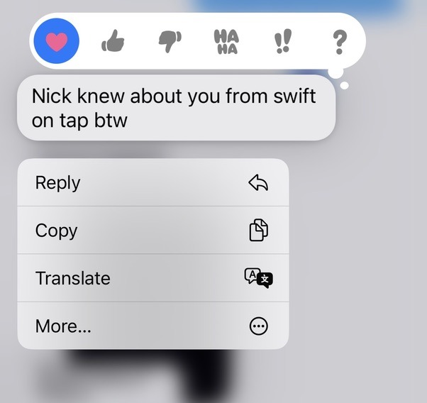 A screenshot of the text “Nick knew about you from swift on tap btw” with the iMessage tapback bar and context menu open, surrounding messages blurred